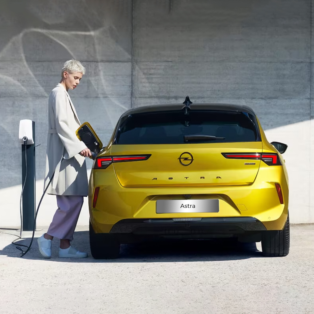 Gele elektrische Opel Astra, naast een laadpaal.